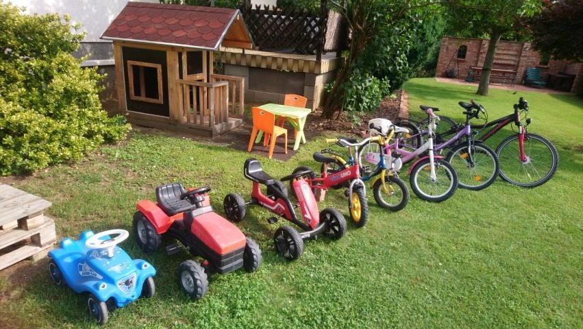 Kinderfahrzeuge und Fahrräder im Garten